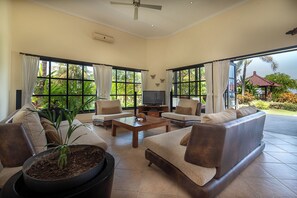 A spacious living area with a sofa set, a coffee table, and a television. - Villa Namasté - Beachfront @ Lovina Beach, 10P, Private Pool, BBQ (Dencarik)
