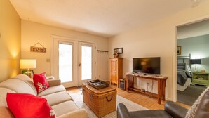 A living room with a sofa, a coffee table, a TV, and a wicker basket.