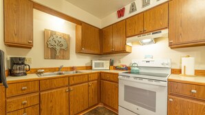 A kitchen with wooden cabinets, a microwave, a stove, and a sink.