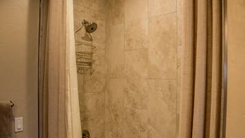 A shower area with a glass door, a towel rack, and a showerhead.