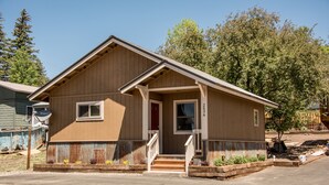A single-story wooden house with a front porch, a small front yard, and a satellite dish on the roof.
