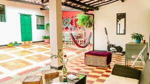 A spacious lobby with a checkered floor, wicker furniture, and a hammock. - Green Door Hostal San Gil - Hostel (San Gil)