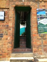 Un edificio de ladrillo con puerta verde y un cartel anunciando un hostal.