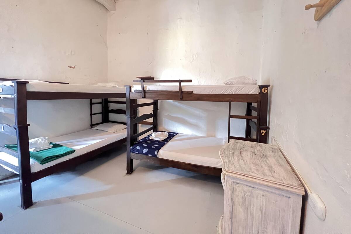 Habitación con literas de madera y ropa de cama blanca.