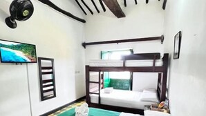 A room with bunk beds, a green bedspread, a white bedspread, a television, and a framed picture on the wall. - Green Door Hostal San Gil - Hostel (San Gil)