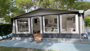 Un espace extérieur abrité, équipé d’une table et de chaises, d’un lave-linge et d’une enseigne portant le nom « Rossini ».
