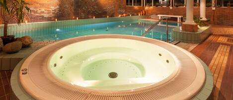 Un espacio de spa con hidromasaje, piscina y pared de ladrillo con diseños en arco.