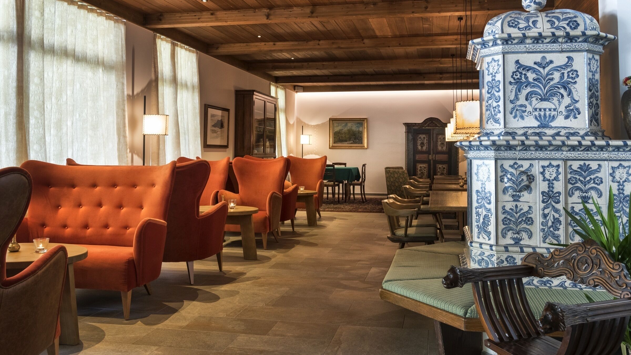 A cozy interior with orange upholstered sofas, a wooden coffee table, and a decorative blue and white ceramic piece.
