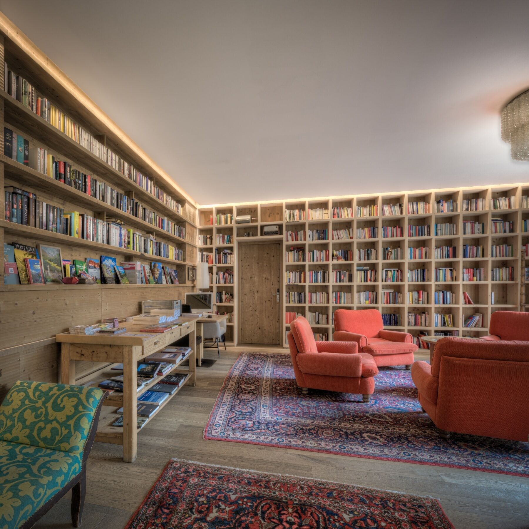 A library with multiple bookshelves, a wooden desk, and seating areas.