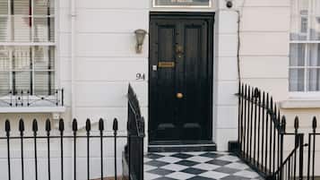 A black door with a sign above it reading 'The Warwick Hotel by Nestor.'