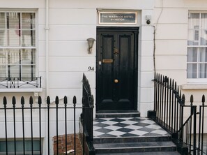 A black door with a sign above it reading 'The Warwick Hotel by Nestor.' -  The Warwick by Nestor (London)