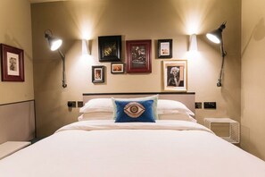A hotel room with a bed, wall-mounted lamps, and framed pictures. -  The Warwick by Nestor (London)
