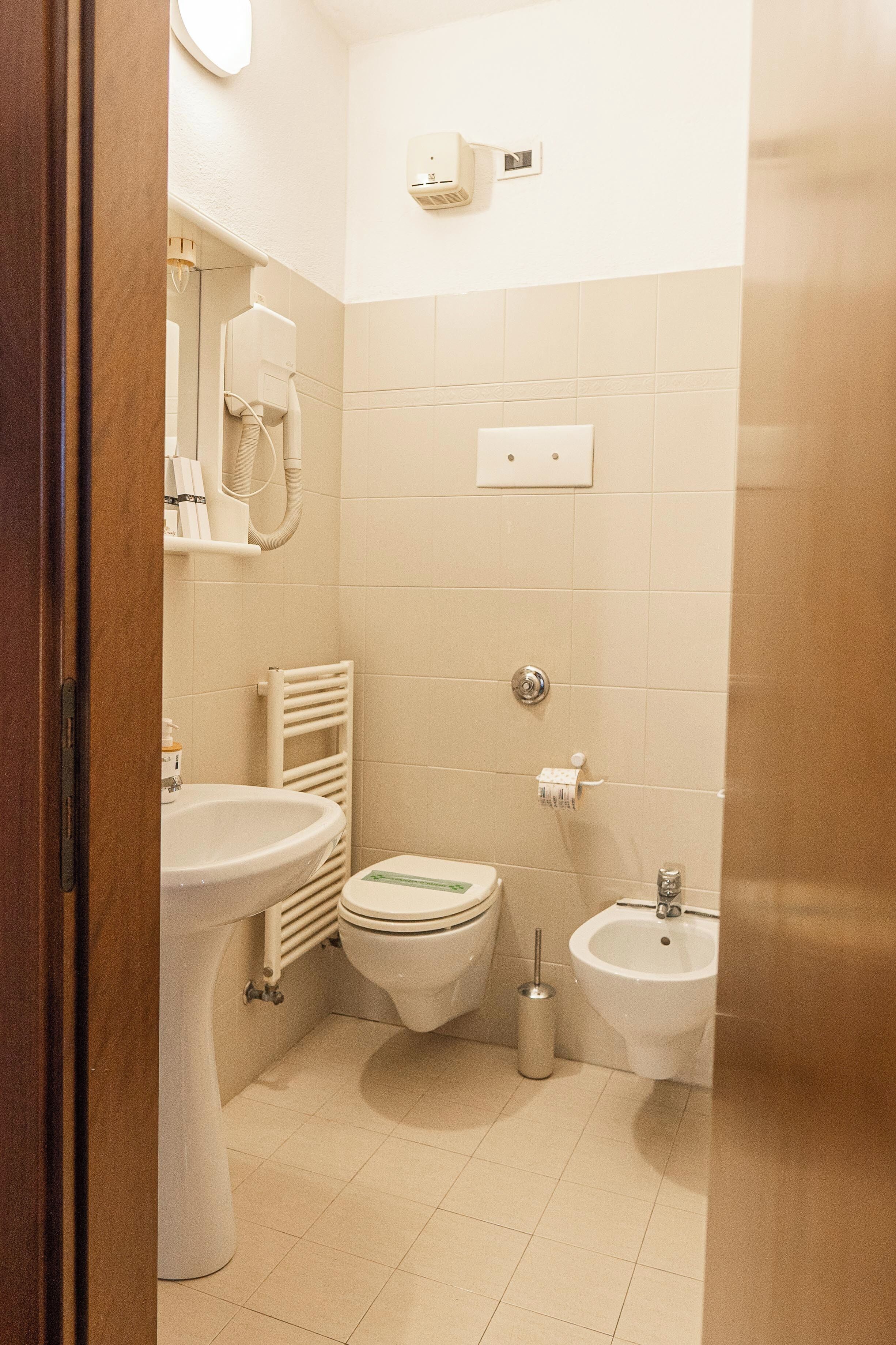 Een compacte, schone badkamer met toilet, bidet en wastafel.