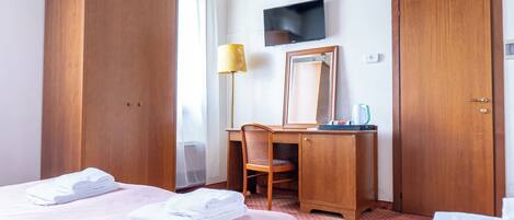 Une chambre d’hôtel avec deux lits, un bureau, une chaise, une télévision et une armoire.