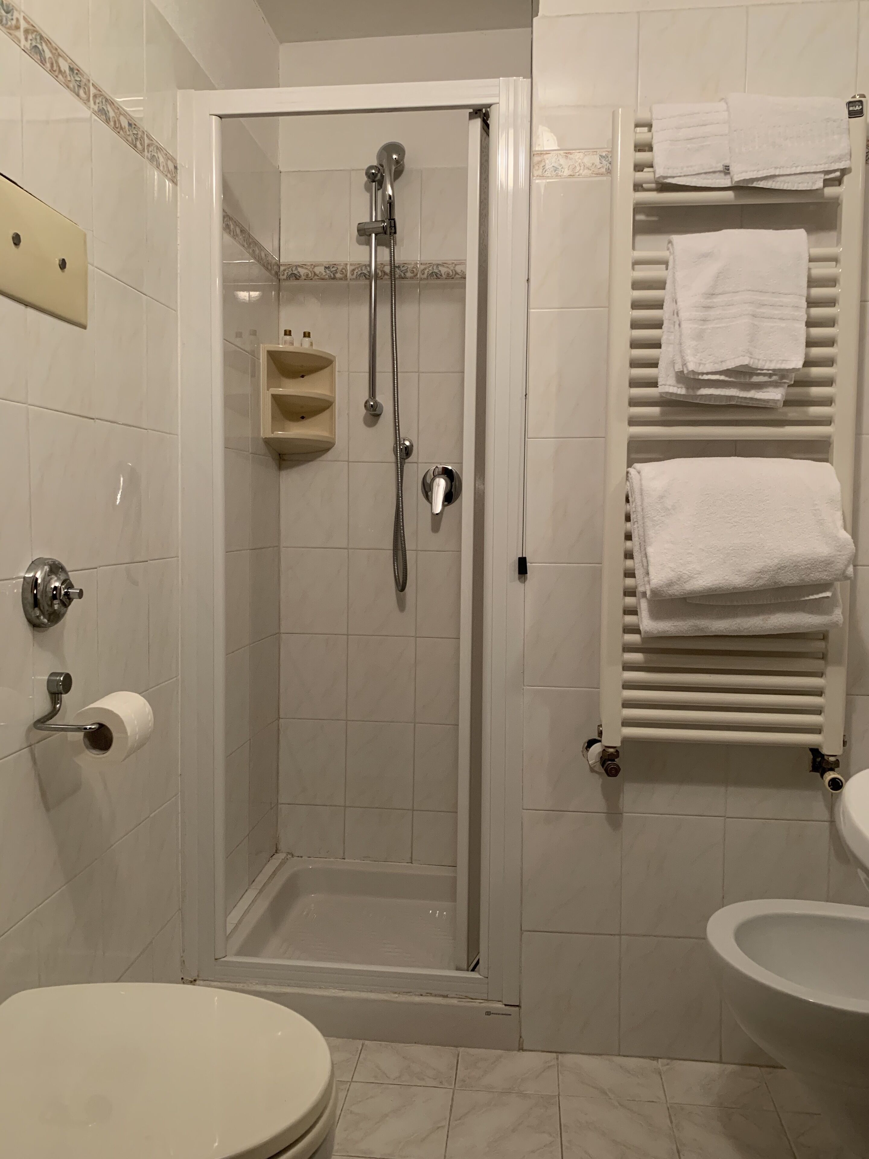 A bathroom with a shower, toilet, sink, and towel rack.