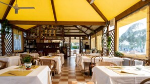 Un restaurante con suelo a cuadros, manteles blancos y sillas de mimbre.