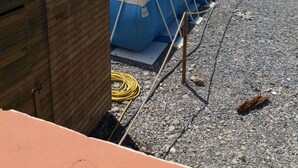 Una piscina con cubierta de madera y sillones de descanso, con vista a una playa con sombrillas.