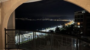 A balcony with a view of a cityscape at night, including a waterfront and distant mountains. - Cannes holiday apartment 606 with balcony, sea view, A/C and parking (Provence-Alpes-Côte-D’Azur)
