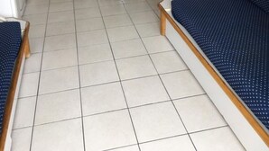 A small, clean room with a bed, a desk, and a chair. There is a TV mounted on the wall and a small table with a plant. - Cannes holiday apartment 606 with balcony, sea view, A/C and parking (Provence-Alpes-Côte-D’Azur)