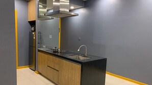 A modern kitchen with a black countertop, wooden cabinets, and a stainless steel range hood.