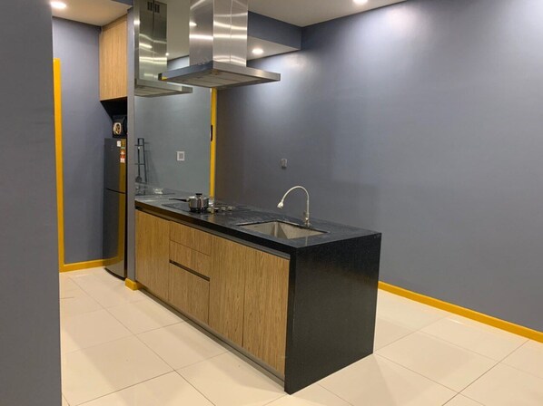 Una cocina moderna con encimera negra, armarios de madera y campana extractora de acero inoxidable.