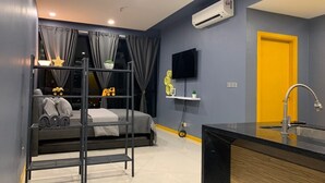 A modern bedroom with a bunk bed, a bedside table with a lamp, a TV, and an air conditioning unit.