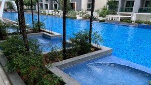 A swimming pool with a tiled edge, surrounded by greenery and modern buildings in the background.