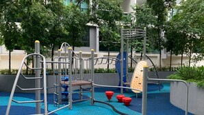 A playground with a blue rubberized surface, metal climbing structures, and red and blue play equipment.