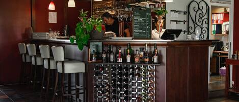 Eine Bar mit Weinkühler, Barhocker und einem Barkeeper.
