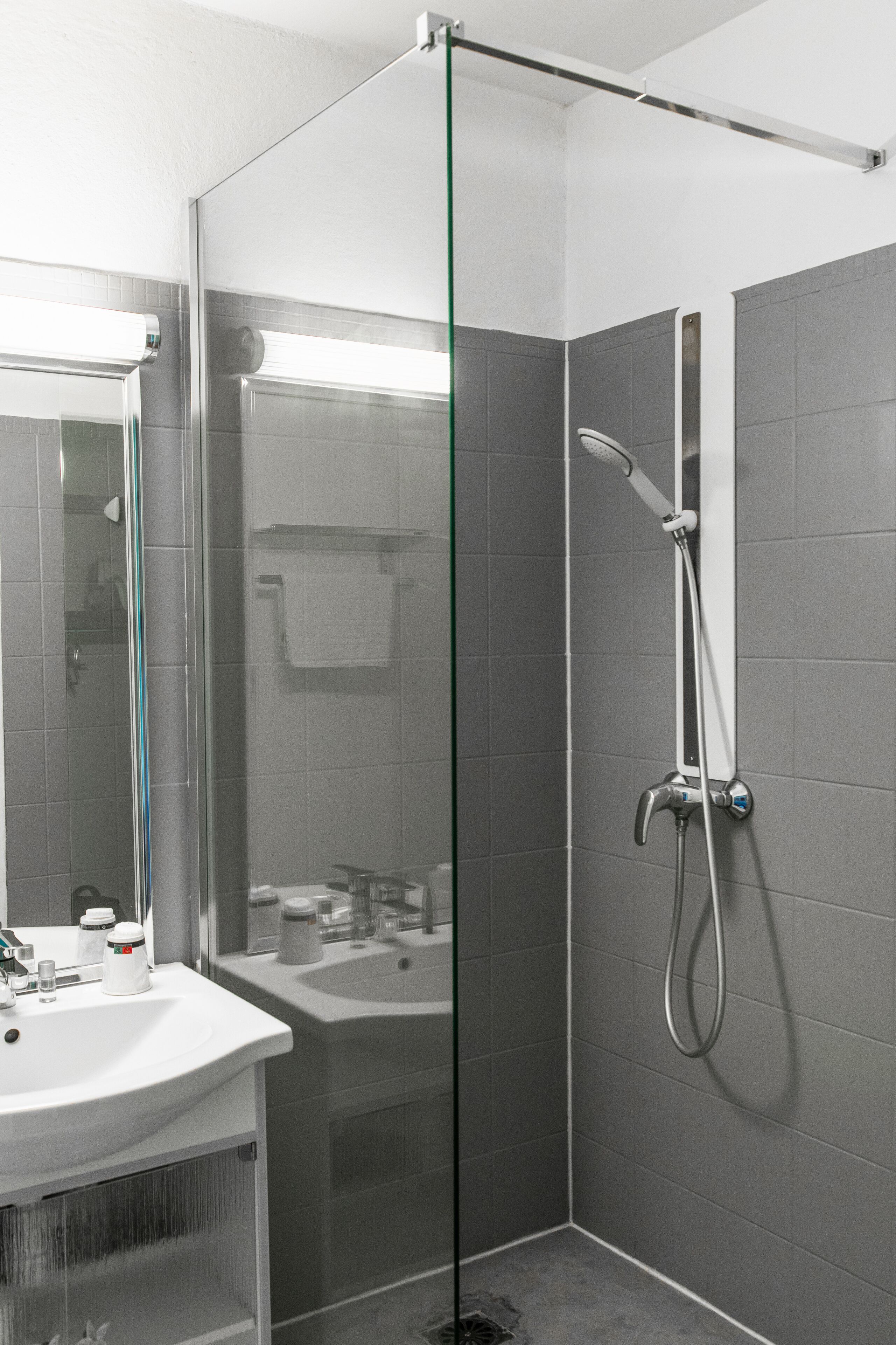 Een moderne badkamer met een douche met glazen wand, een wastafel en een spiegel.