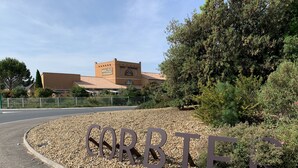 A hotel entrance with a gravel path leading to the building, surrounded by greenery and a fence. - Le Mas De Gaujac (Lezignan-Corbieres)