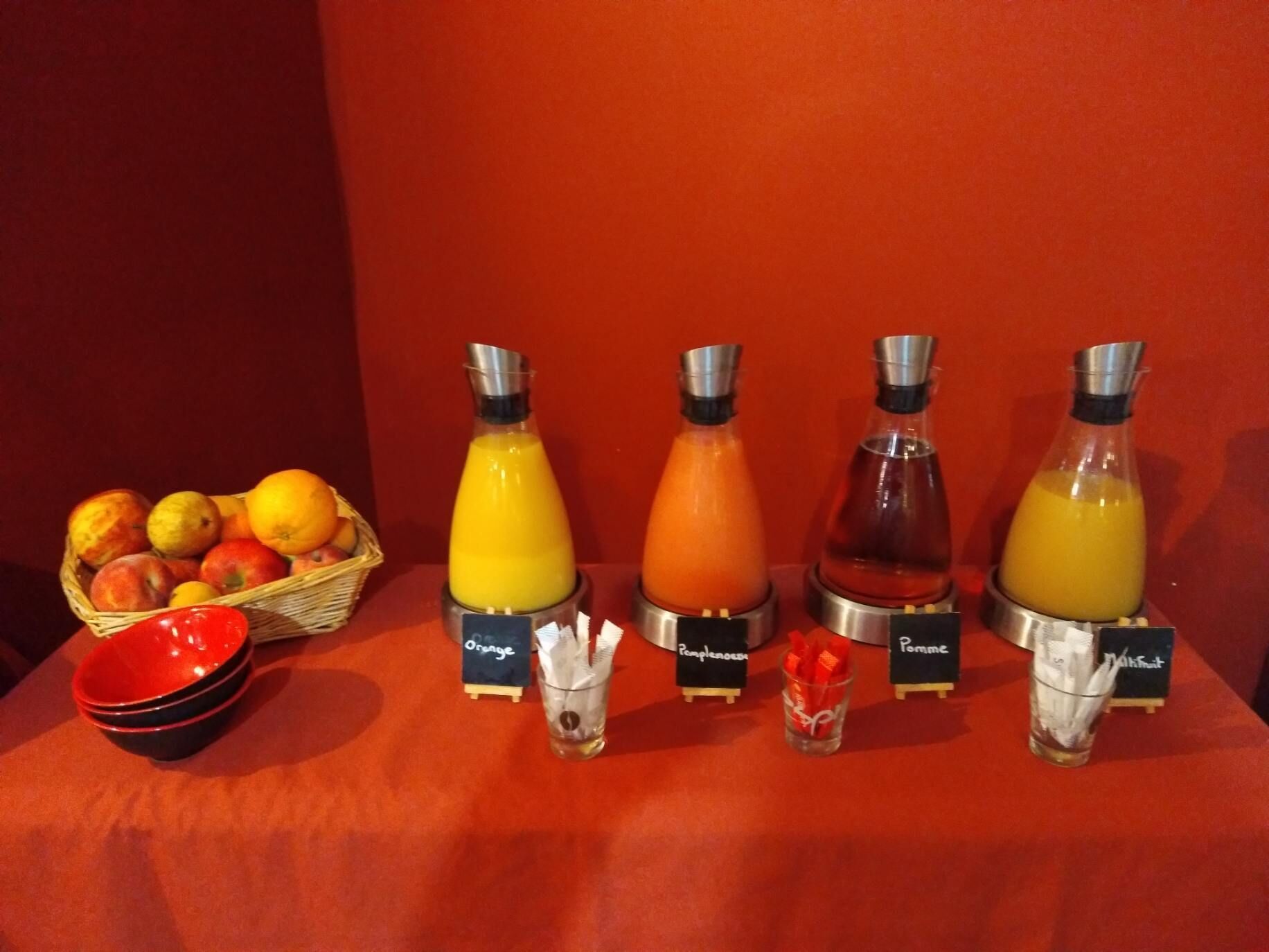 Una barra de jugos amb diverses opcions de suc de fruita i una cistella de fruites.