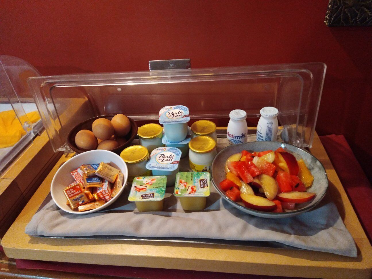 Bandeja de desayuno con huevos, yogur, salsas y fruta.