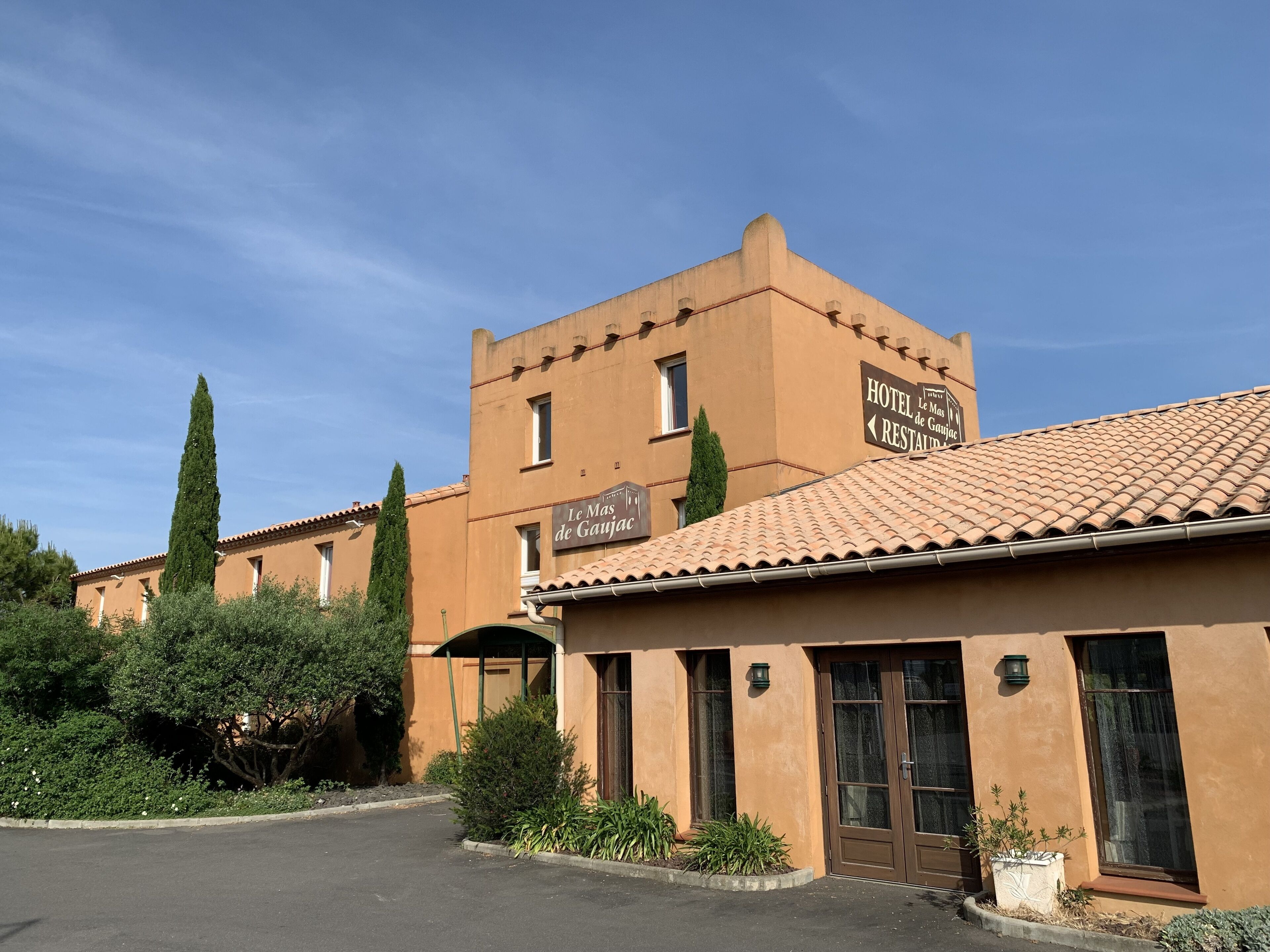 A hotel building with a sign reading "HOTEL Le Mas de Gaujac RESTAURANT".