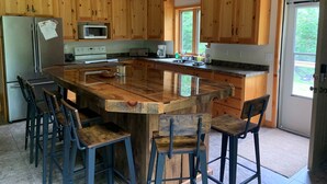 A spacious kitchen with wooden cabinets, a large island, and bar stools. - Snowmobile, Skiing, and Outdoor Paradise/Cabin (Niagara)