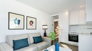 Un salon moderne avec un canapé, une table basse et des œuvres d’art accrochées au mur.