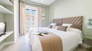 Une chambre avec un lit, une télévision, une bibliothèque et un balcon avec vue.