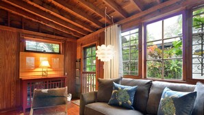 A cozy cabin interior with a wooden ceiling, a sofa with turtle-themed pillows, a chair, and a window with a view of greenery. - ~ SOLARIS PAIR-A-DISE ~ A garden lover’s dream on a quiet Key West lane. (Key West)