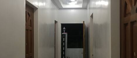 Ein Flur mit weißen Wänden, Holztüren und einer Decke mit eingelassenen Leuchten.