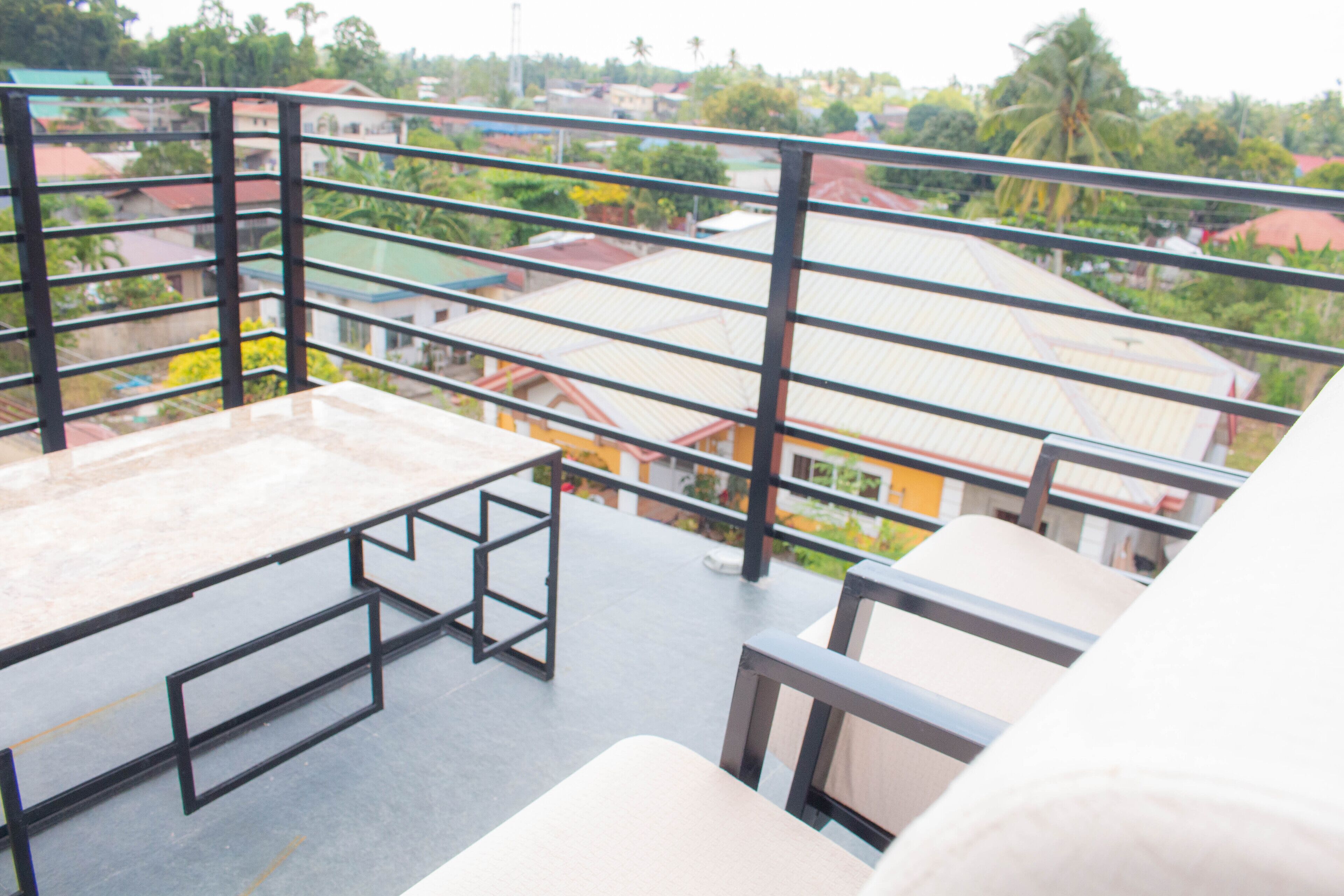 A balcony with a metal railing, a table, and chairs.