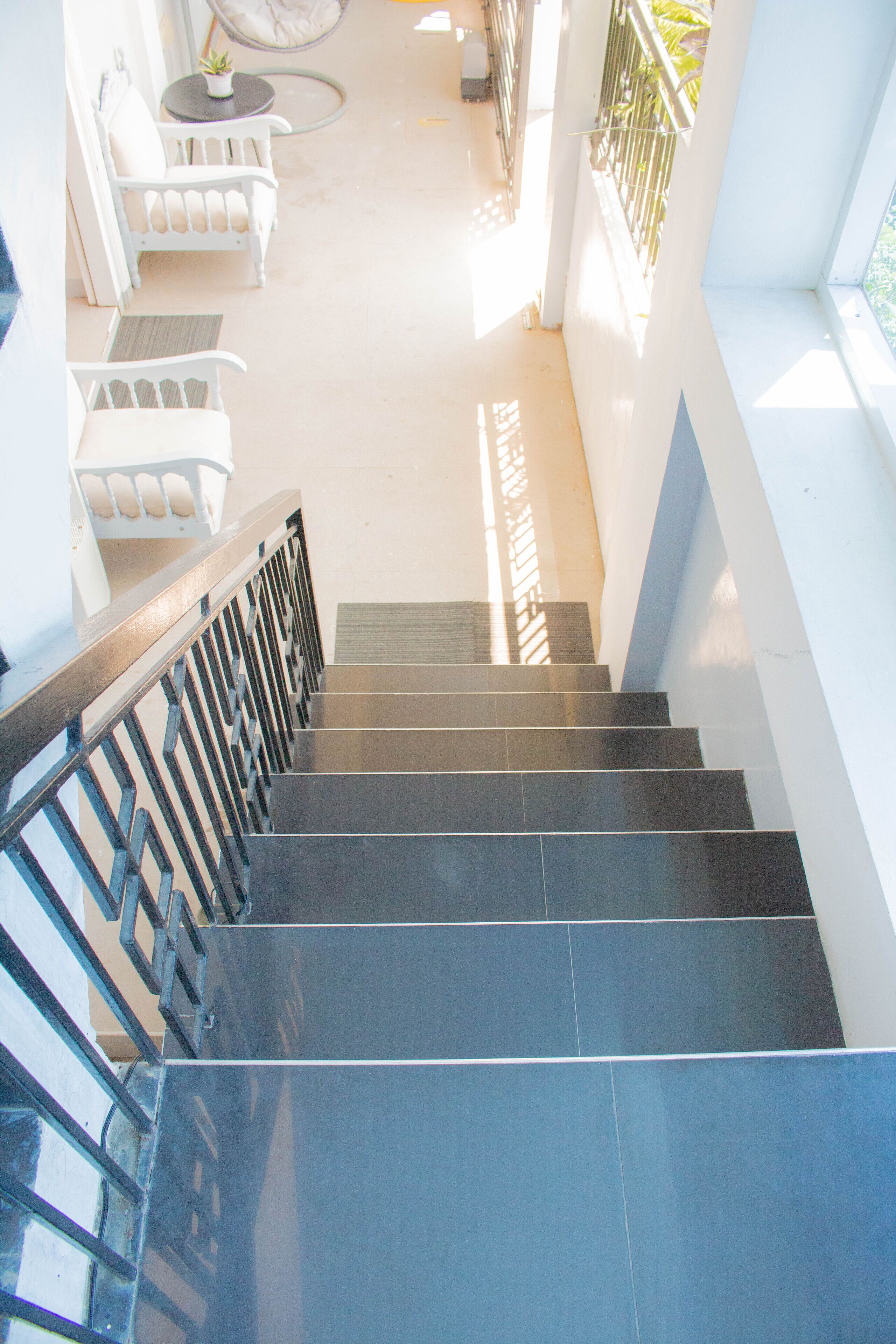 A staircase with black steps and a metal railing leading to a balcony.