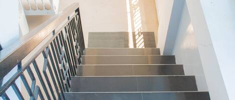 A staircase with black steps and a metal railing leading to a balcony.