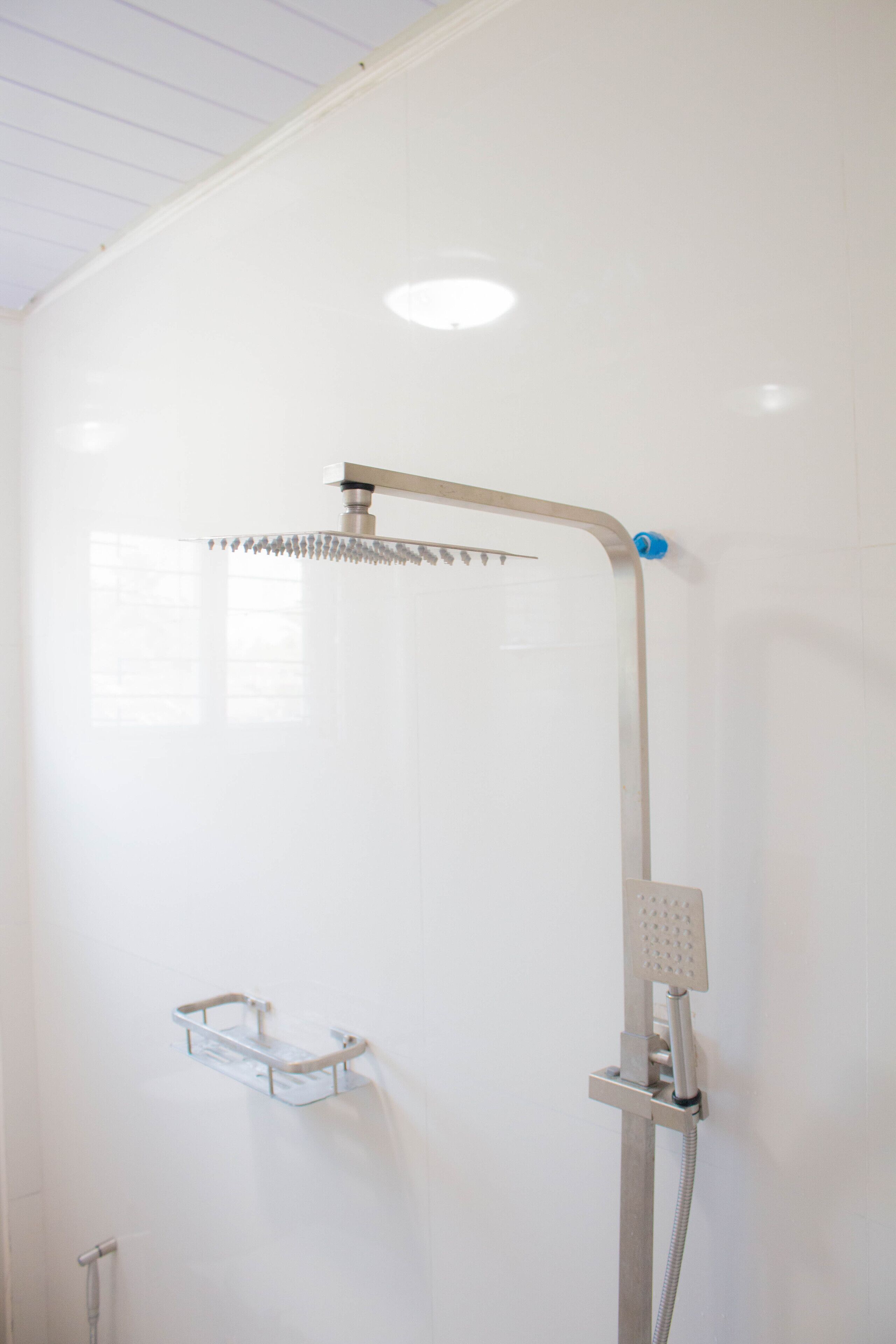 A shower with a handheld showerhead and a wall-mounted control panel.