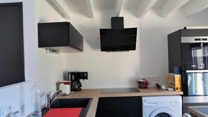 Una cuina compacta amb rentadora, cafetera i microones.
