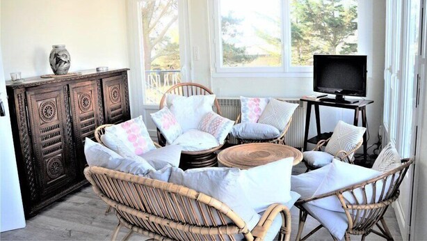 A cozy room with wicker furniture, a television, and a cabinet.