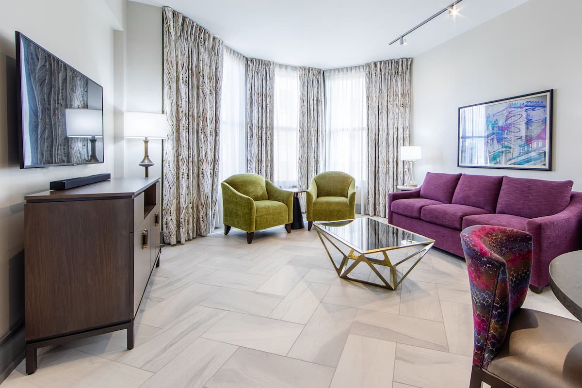 Un salon moderne comprenant un canapé, deux fauteuils, une table basse et un téléviseur.
