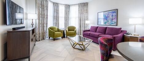 A modern living room with a sofa, two armchairs, a coffee table, and a TV.