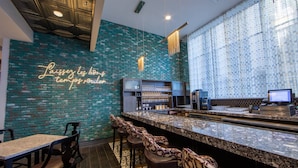A bar area with a neon sign, a brick wall, and a counter with bar stools.