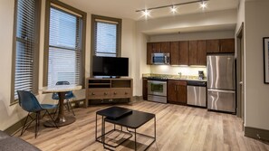 A modern kitchen with stainless steel appliances, a dining area with a table and chairs, and a TV on a wooden stand. - Holiday Inn Club Vacations New Orleans Resort by IHG (New Orleans)