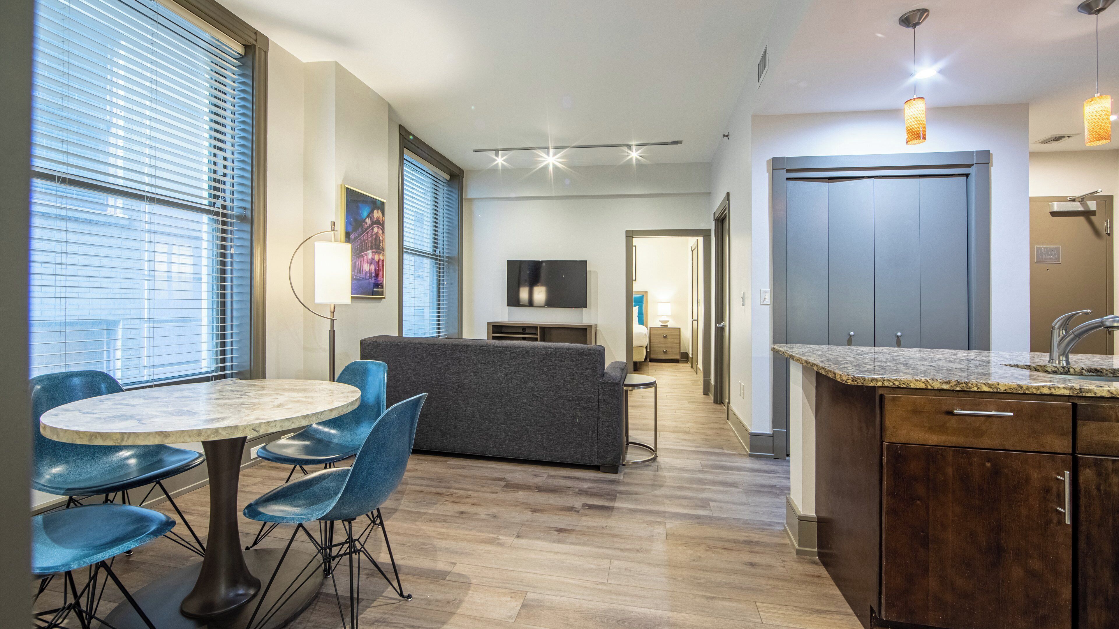 Una habitación de hotel moderna con comedor, sofá, televisor y espacio para la cocina.